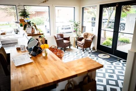 The shop’s front room: a wooden counter, two leather armchairs and a patterned tile floor